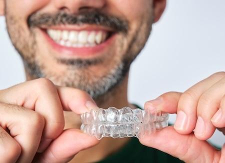 cosmetic dental care services dedham | man holding invisalign